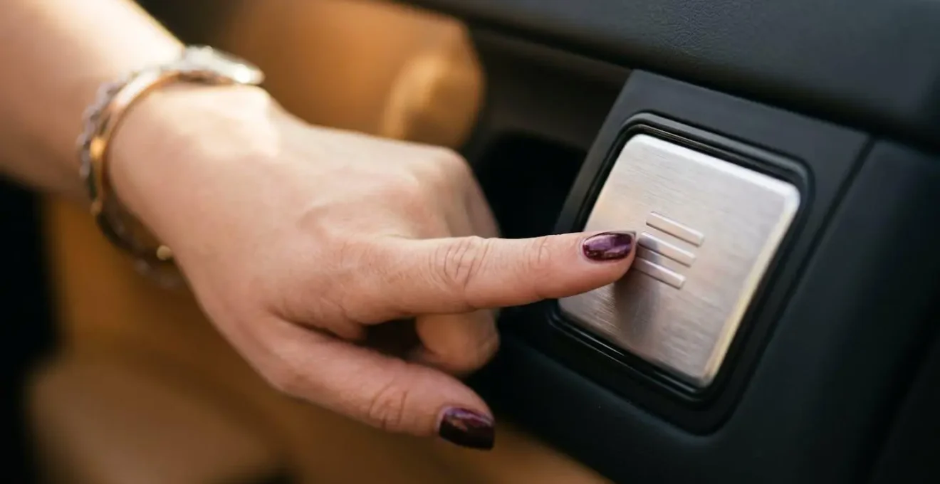 Vue macro des commandes de mémorisation de siège avec main féminine actionnant le bouton