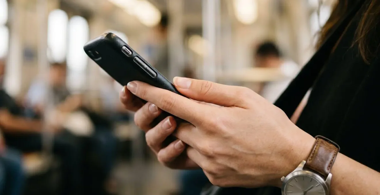 Gros plan sur des mains tenant un smartphone montrant une interface de planification de trajet avec une montre visible au poignet