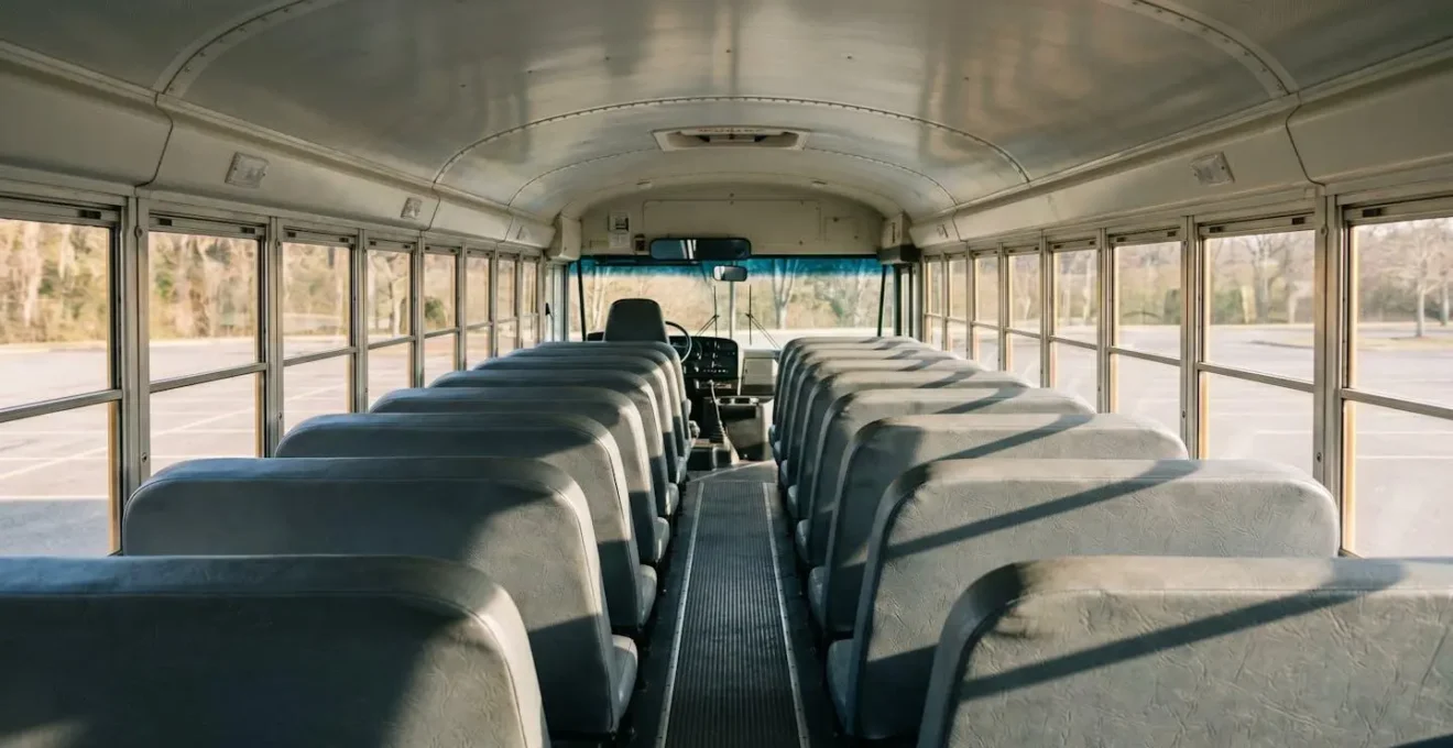 Vue intérieure d'un bus scolaire montrant une conductrice utilisant le rétroviseur panoramique pour surveiller les enfants