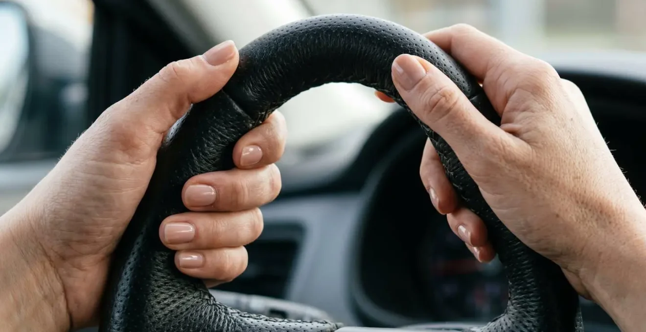 Vue rapprochée des mains d'une femme positionnées correctement sur le volant d'une voiture à 10h10.