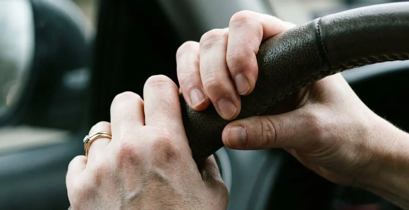 Macro sur les mains crispées d'une conductrice sur le volant montrant la tension