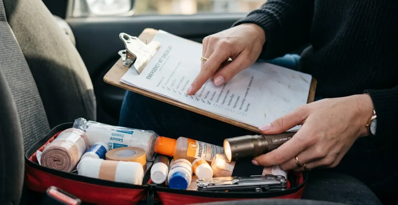 Inspection visuelle par une femme d'une trousse de premiers secours automobile avec dates de péremption visibles en Belgique